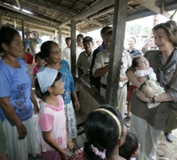 Su Majestad la Reina sostiene en brazos un bebé durante su recorrido por un poblado de la Isla de Nías