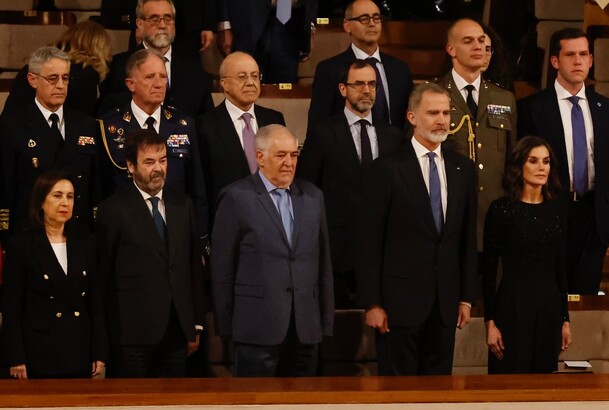 Sus Majestades los Reyes, acompañados por las autoridades asistentes al acto, en el momento de la interpretación del Himno Nacional