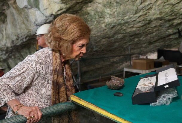 La Reina Sofía observa algunos elementos hallados en la Cueva Mayor